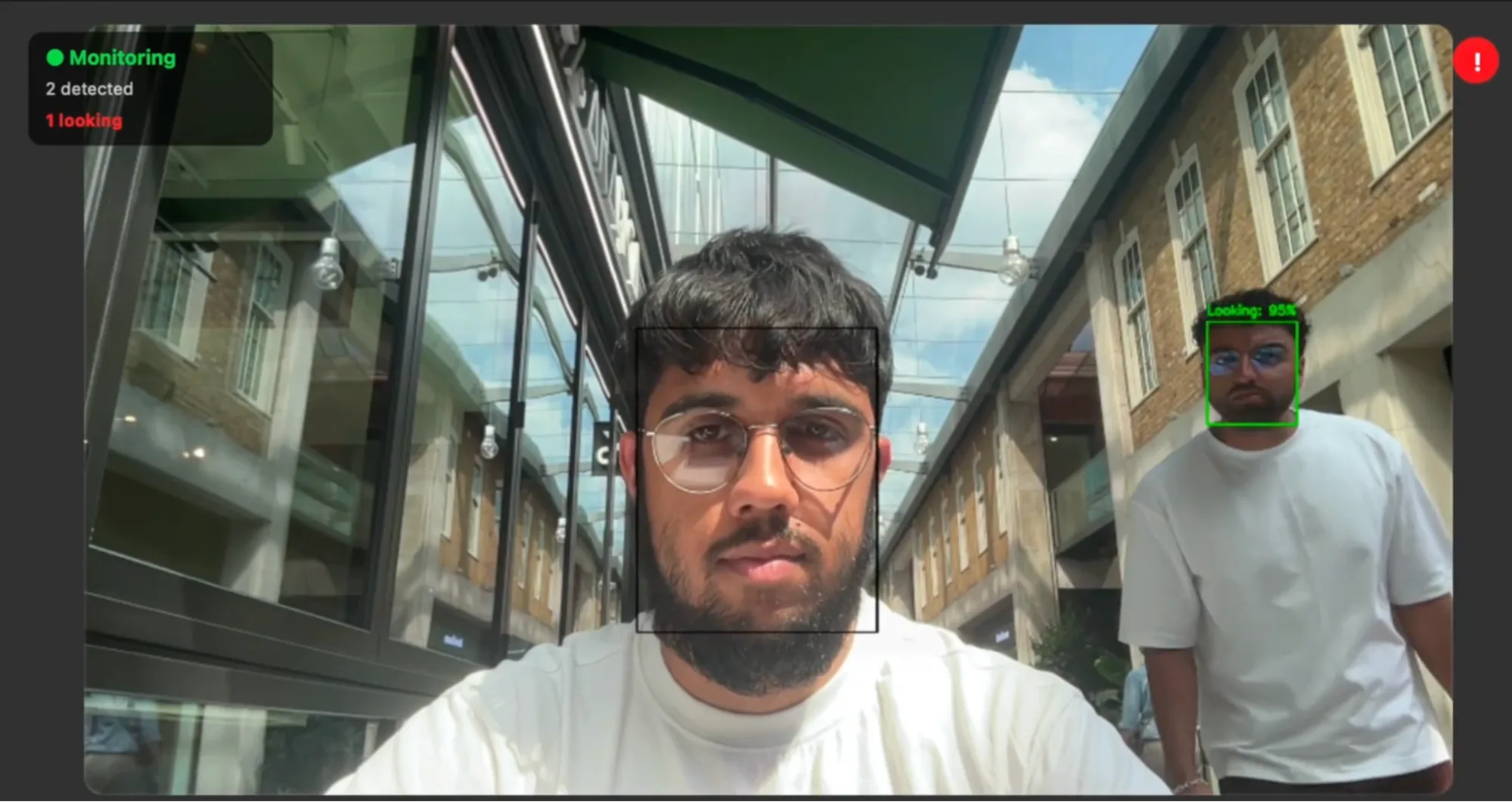 Photo of someone working on their laptop taken from their webcam, with a shoulder surfer walking by and glancing at the laptop screen